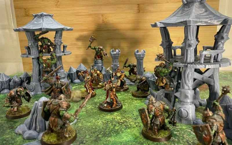 Décors wargame imprimés en 3D avec figurines fantastiques en combat, tours et ruines.